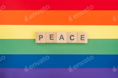 Preview: top view of pease lettering peace made of wooden cubes on paper rainbow background