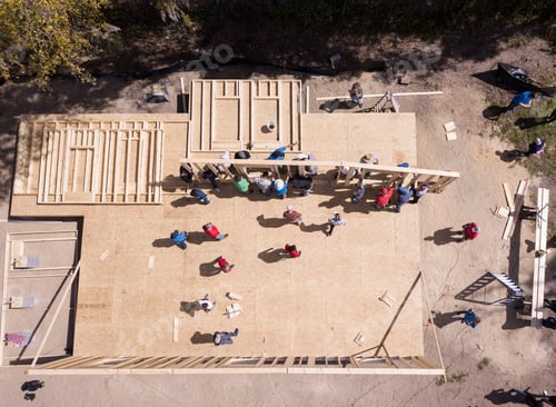 Preview: Team building effort as a group of people raise a wall on a new