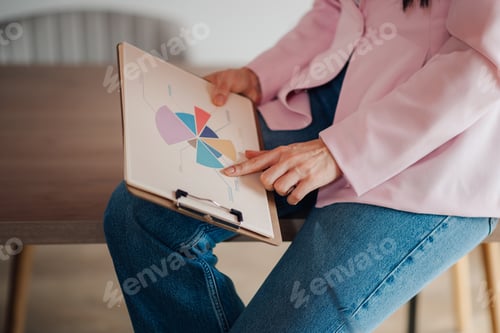Preview: Businesswoman analyzing financial pie chart on clipboard