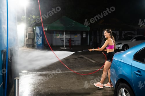 Preview: Young woman washing blue car at car wash