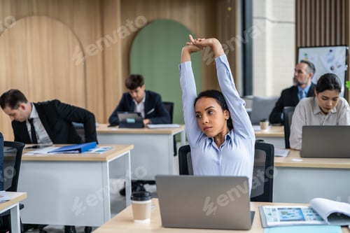 Preview: Young Latino businesswoman stretching body while working in the office.