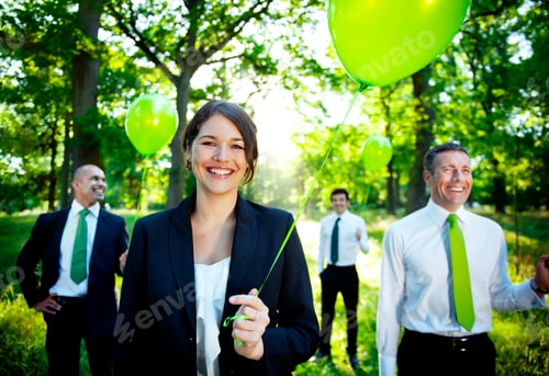 Preview: Business people holding green balloon in forest.