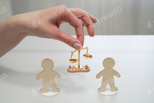 Preview: Hand holds a scale of justice between two figures of people. Concept of justice
