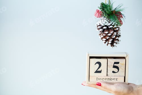 Preview: Woman in hand holds Christmas decorations on light background