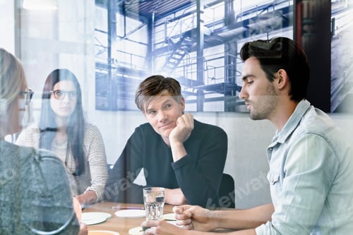Preview: View through glass of colleagues at meeting in conference room