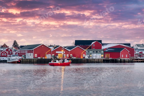 Preview: Beautiful rorbuer fishing village and fishing boat on coastline in the sunset at Reine town