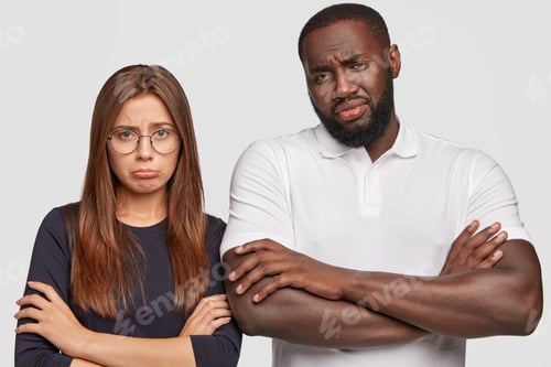 Preview: Horizontal shot of displeased young multiethnic couple have miserable looks as draw distrubing pictu