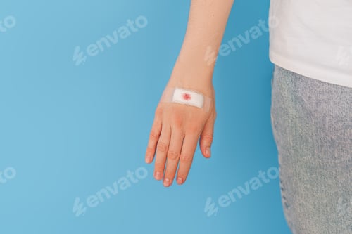 Preview: Girl with plaster on the brush hand opposite the blue background