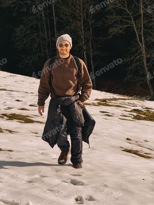 Preview: A man wearing a brown sweater and a white hat is walking on a snowy hill