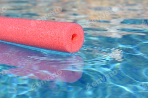 Preview: Pink pool noodle floating on water in swimming pool