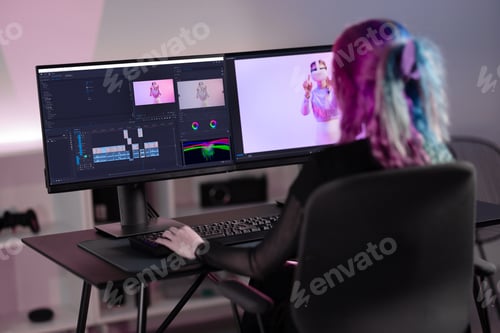 Preview: Professional female film editor editing video on his personal computer with two displays in modern