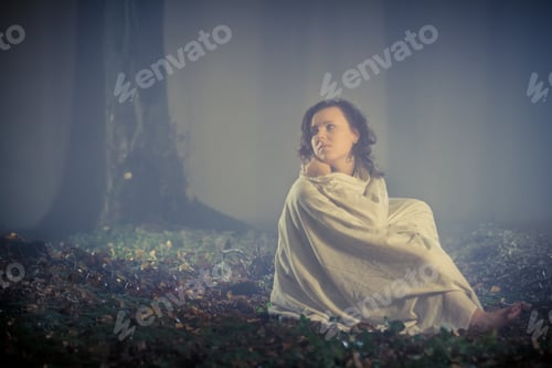 Preview: Frightened woman looks in a dark forest