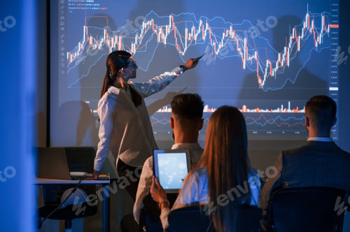 Preview: Showing the plan on the projector. Female leader talking to employees in office
