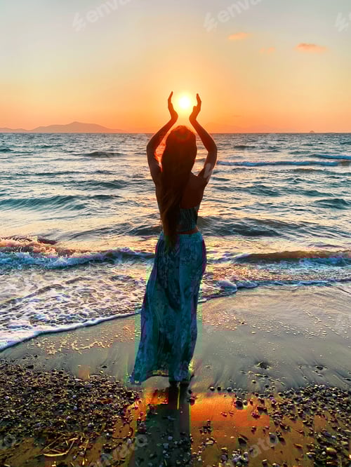 Preview: silhouette of a young woman holding a sun above the sea