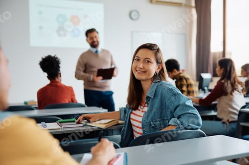 Preview: Happy college student during a lecture in the classroom looking at camera.