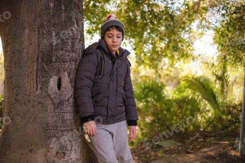 Preview: Thoughtful Boy in Winter Attire by a Tree