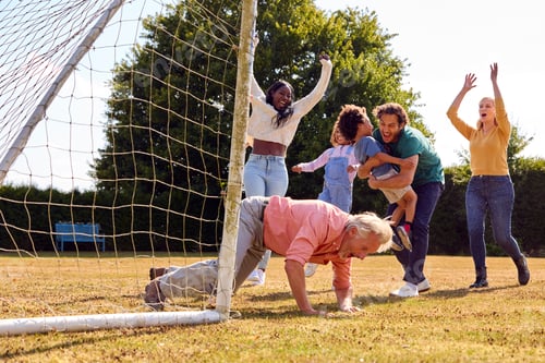 Preview: Multi-Generation Family At Home In Garden Playing Football Or Soccer Together