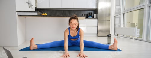 Preview: Portrait of young woman does gymnastics training at home, workout, making splits on rubber fitness