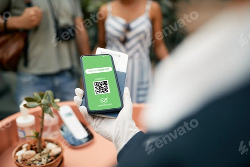 Preview: Close-up of hotel receptionist checking guest's COVID-19 vaccination passport on mobile app.