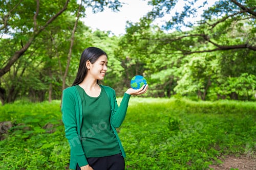 Preview: Forest conservationist holds small globe in hands,symbolizing global responsibility for protecting