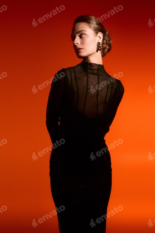 Preview: Elegant woman in stunning black dress captivates with grace amid vibrant orange backdrop