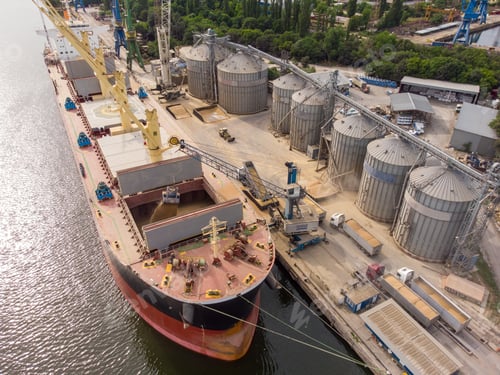 Preview: Loading grain into sea cargo vessel in seaport from silos of grain storage. Aerial view