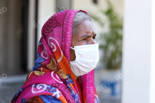 Preview: Old Indian woman sitting outside the hospital wearing a face mask before taking a covid-19 test