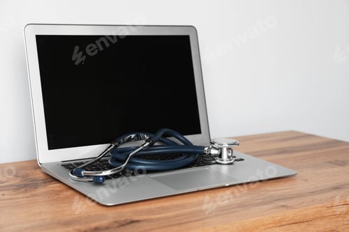 Preview: Laptop with blank screen and stethoscope on table against light background. Computer repair