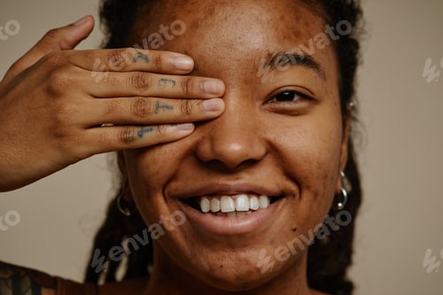 Preview: Close up ethnic young woman smiling candidly with one eye closed