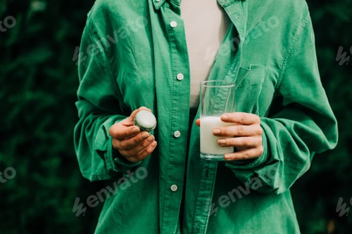 Preview: Woman in green shirt hold macaron cookie and glass of milk