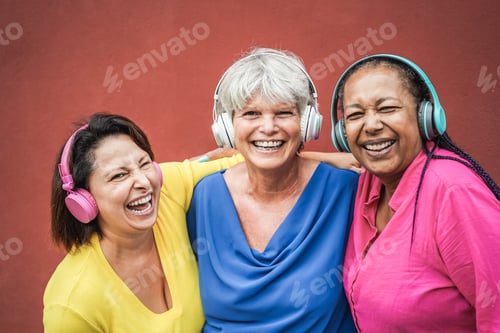 Preview: Multiracial senior friends having fun listening music with headphones - Focus on middle woman face