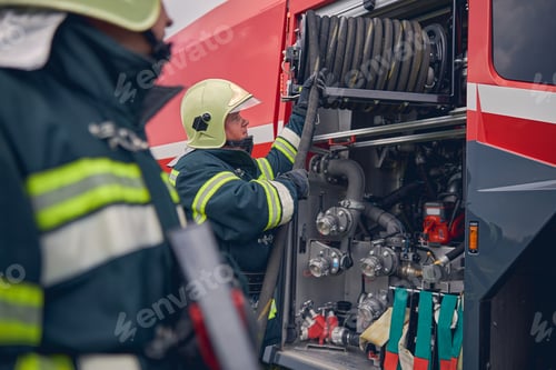 Preview: Fireman wearing safe helmet standing next to the fire engine