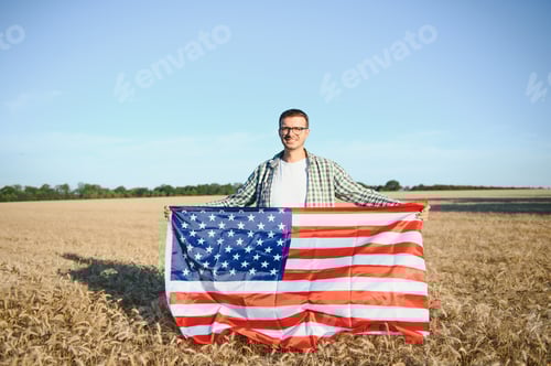 Preview: Young patriotic farmer stands among new harvest.