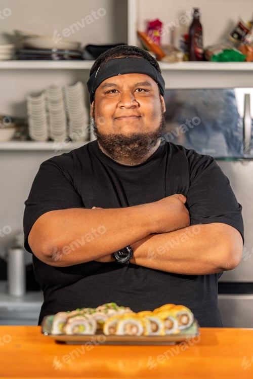 Preview: Sushi chef proudly presenting his delicious maki rolls in restaurant kitchen