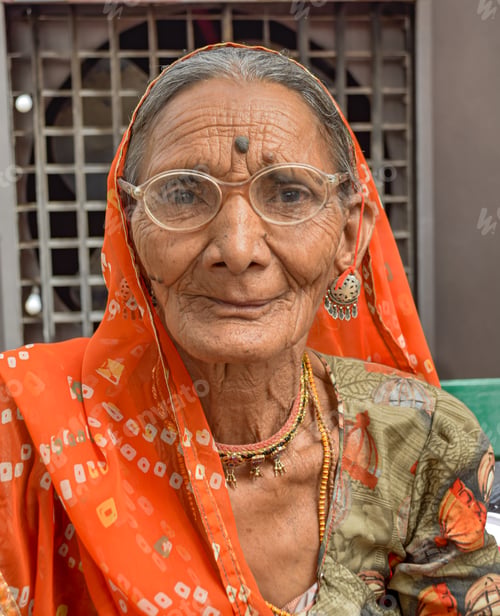 Preview: Indian Woman with beautiful face and orange sari posing with ruins in background