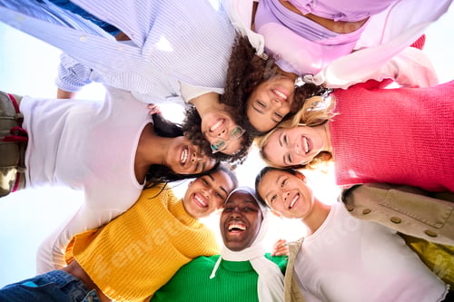 Preview: Low angle of a group of multiracial young women looking at camera standing in a circle smiling