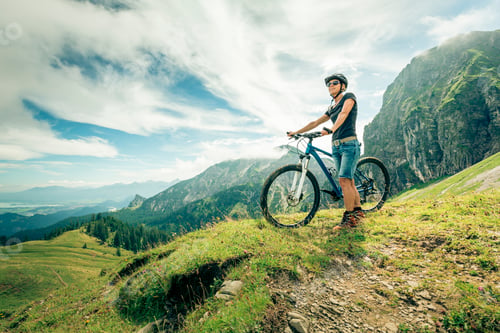 Preview: Germany, Bavaria, Pfronten, woman with mountain bike on alpine meadow near Aggenstein
