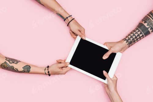Preview: partial view of shopaholics pulling digital tablet with blank screen isolated on pink