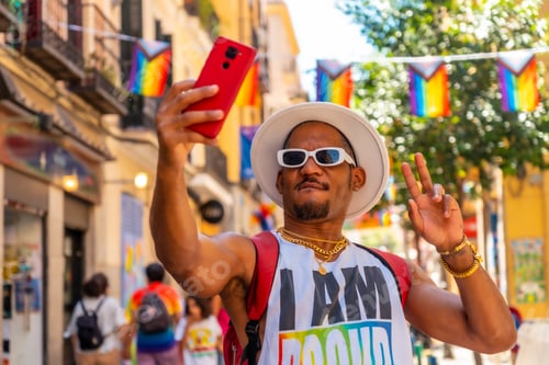 Preview: A gay black man at the pride party taking a selfie with the phone, LGBT flag