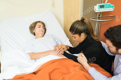 Preview: Depressed Couple Consoling Senior Woman At Hospital