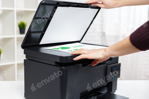Preview: Hand placing documents on flatbed scanner at a desk in a bright office space