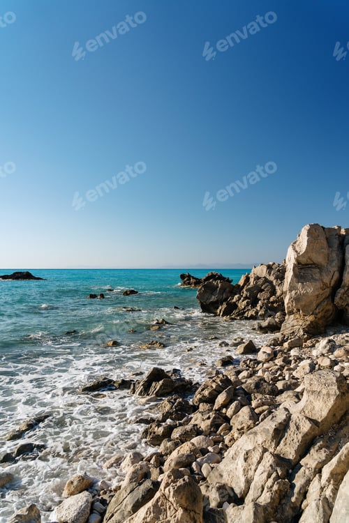Preview: Rocky shoreline with clear blue sea under sunny sky