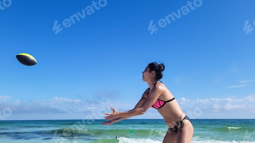 Preview: Young generation X woman with upswept hair in bikini on seashore on vacation having fun by ocean.