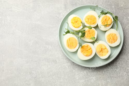 Preview: Hard boiled eggs with microgreens on grey table, top view. Space for text