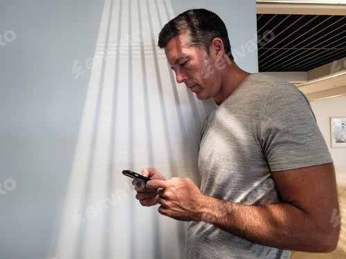 Preview: Man Using Phone While Leaning Against Wall