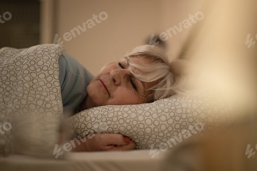 Preview: Senior woman sleeping on bed at night.