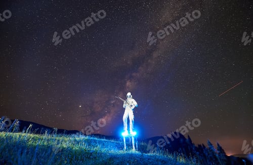 Preview: Astronaut playing guitar under beautiful night sky.