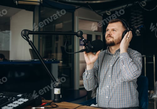 Preview: Handsome happy young male radio host broadcasting in studio, using microphone and headphones