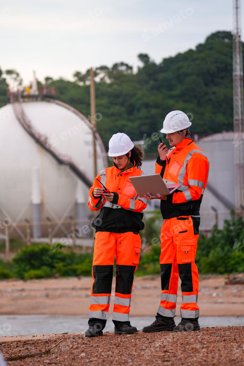 Preview: Two engineers in high-visibility safety gear and hard hats discuss project plans