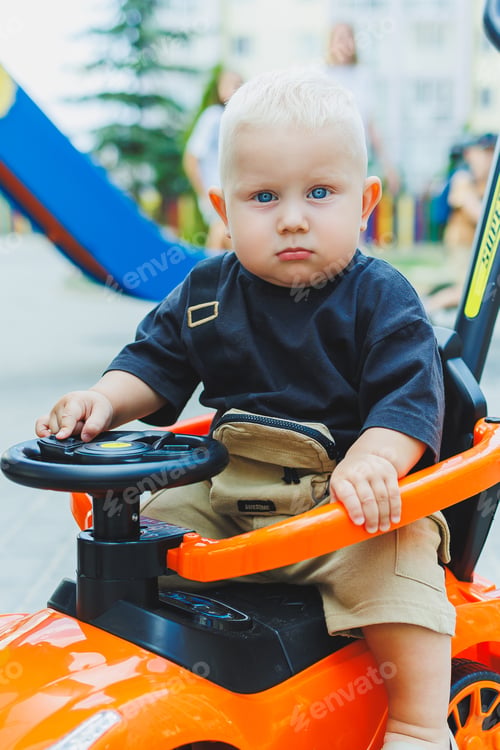 Preview: A little boy, 1 year old, sits in a plastic car. A machine for feeding babies. Tolokar for children.